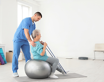 Elderly-Woman-On-Exercise-Ball-using-Resistance-Band.jpg