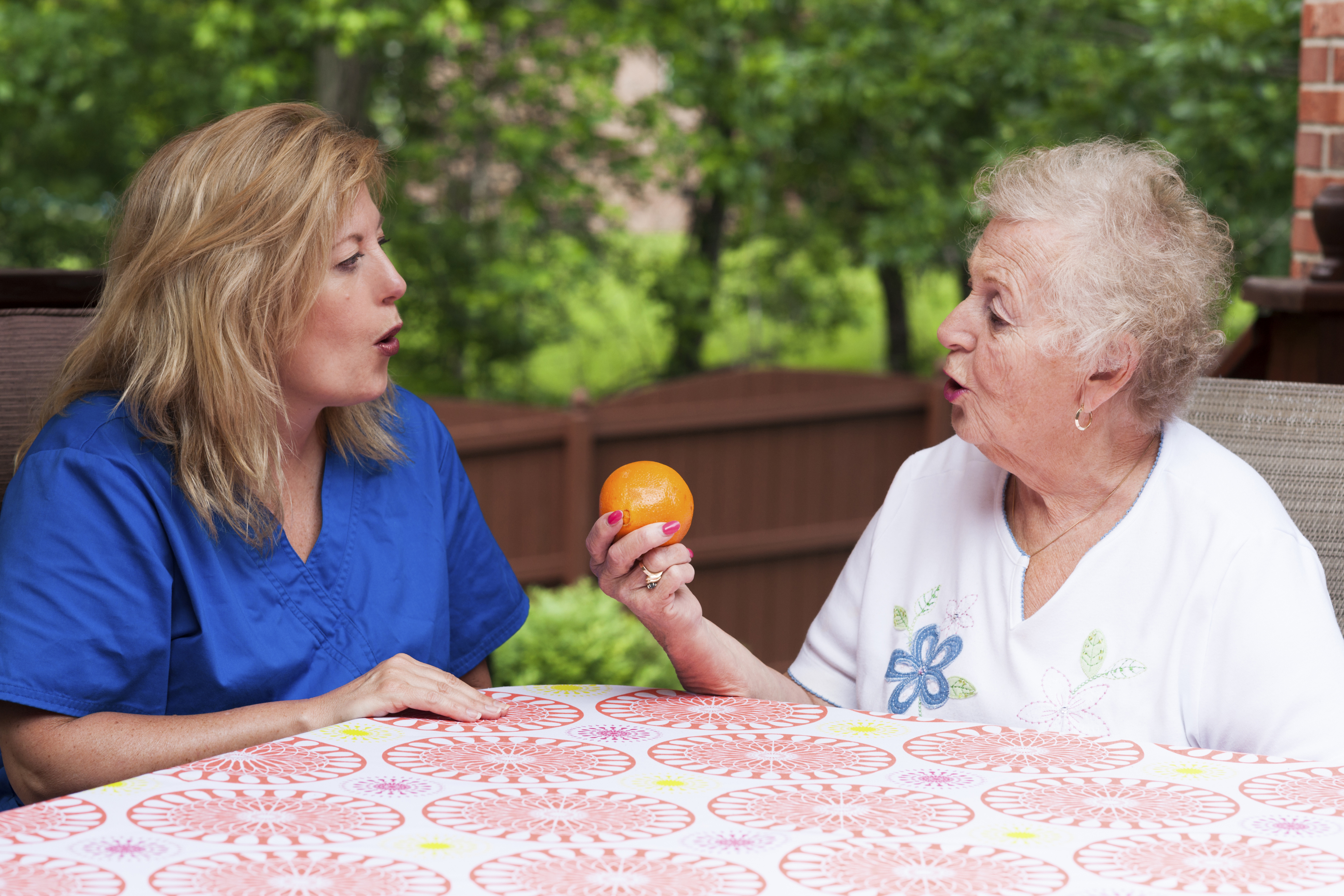 Speech-Therapist-and-Elderly-Woman-Holding-An-Orange.jpg